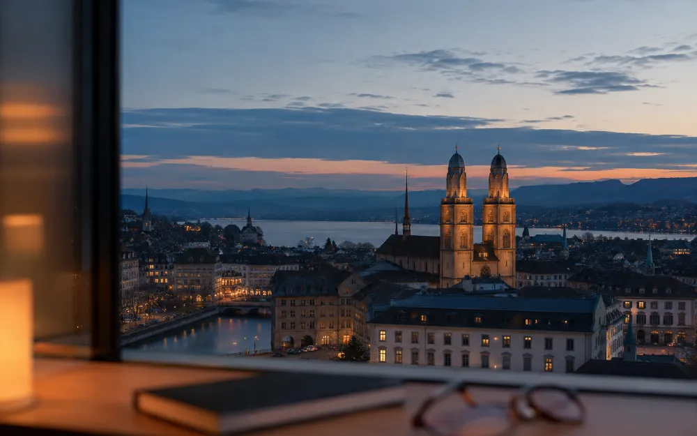 Abendlicher Blick über Zürich mit Notizbuch und Brille am Fenster